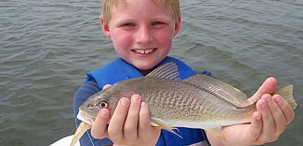Smiling boy with fish caught aboard Rock On Charters.